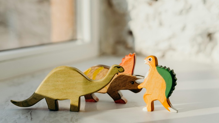 Drei Spielzeugdinosaurier, die so aussehen als würden sie streiten.