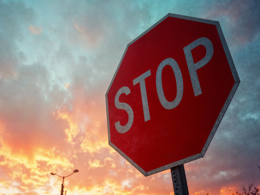 rotes 8-eckiges Stop-Schild vor blau orangenem Himmel